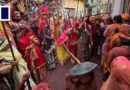 Hindu women playfully beat men with sticks during traditional Holi celebrations