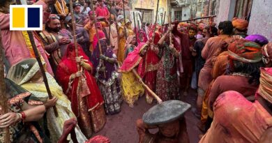 Hindu women playfully beat men with sticks during traditional Holi celebrations